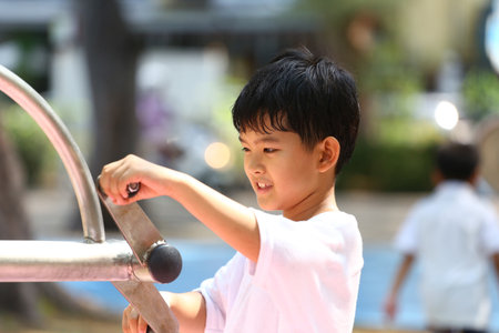 A young boy plays joyfully with playground equipment, embodying the spirit of childhood. His bright smile and engagement capture the essence of outdoor fun and exploration.の写真素材