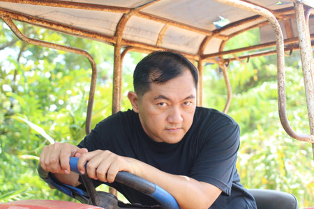 A serious man operates a tractor in a lush green environment, showcasing dedication to farming and...