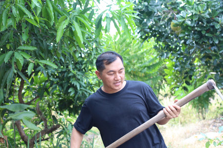 A man engages in orchard work, surrounded by lush greenery and trees. This scene captures the essence of rural life and commitment to agriculture.の写真素材