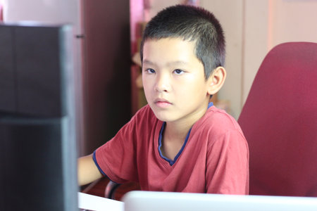 A young boy focused on his computer at home, showcasing dedication to learning and technology. Perfect for educational and lifestyle themes.の写真素材