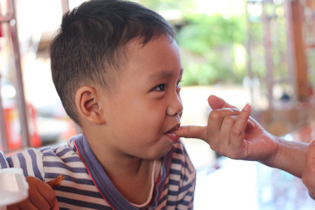 A joyful child savors a snack, engaging in a gentle interaction. This candid moment captures innocence and happiness, highlighting playful childhood.の写真素材