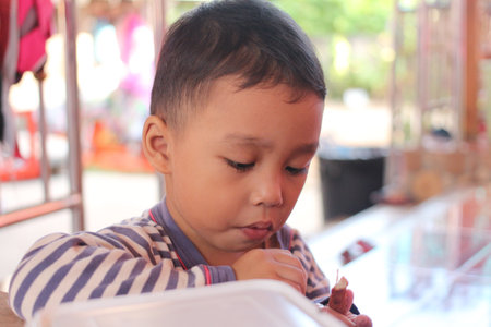 A young child immersed in a creative activity, showcasing focus and curiosity. Captures the essence of childhood learning and artistic exploration in a vibrant indoor setting.の写真素材