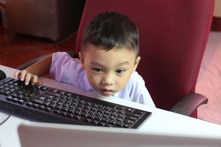A young child curiously examines a computer screen, showcasing engagement and wonder in a home environment. A snapshot of modern childhood exploration and learning.の写真素材