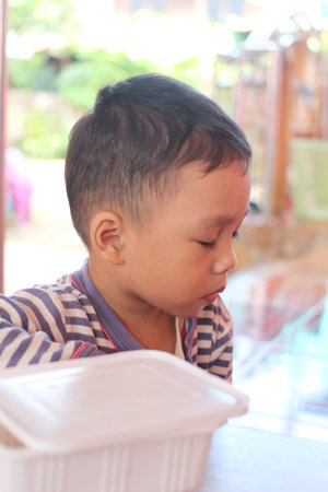 A thoughtful young boy pauses in a casual indoor setting, showcasing innocence and emotion. This serene moment captures the beauty of childhood and contemplation.の写真素材