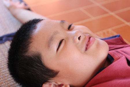 A cheerful boy lies on a comfortable surface, radiating happiness and serenity. The relaxed atmosphere captures the joy and innocence of childhood moments.の写真素材
