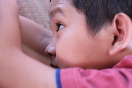 A close-up portrait of a young boy deeply focused on an activity, capturing his curious expression and the warmth of a cozy environment around him.の写真素材