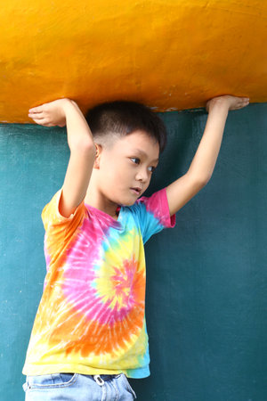 A young boy showcases his colorful tie-dye shirt while posing playfully outdoors. His expression captures the essence of childhood joy and creativity.の写真素材