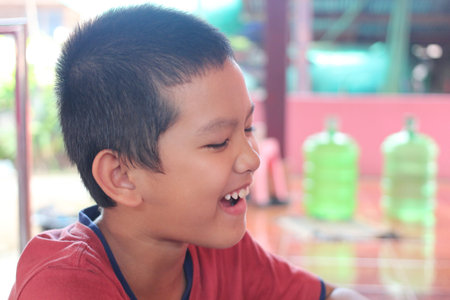 This image captures a joyful young boy laughing, showcasing a candid moment of happiness. The vibrant setting enhances the sense of playfulness and innocence.の写真素材
