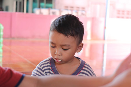 A young boy displays a thoughtful expression while engaging in an indoor activity, showcasing moments of childhood curiosity and exploration.の写真素材