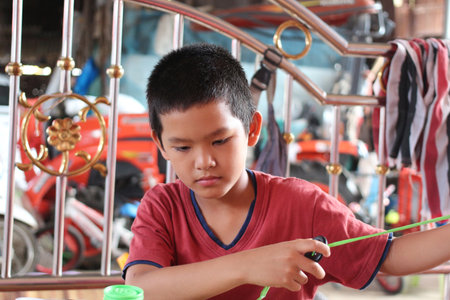 A young boy is focused on a creative activity at home, showcasing concentration and joy. The image captures the essence of childhood exploration and fun.の写真素材