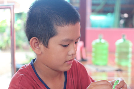A young boy focuses intently on a craft activity, showcasing his creativity and engagement. The scene captures the essence of childhood and learning through play.の写真素材