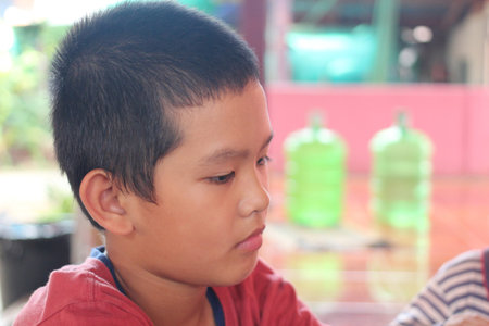A portrait of a thoughtful boy in a vibrant setting, reflecting deep concentration. The image captures youth and innocence in a candid moment of reflection.の写真素材