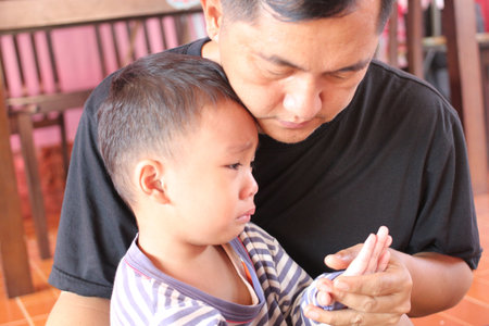 A heartfelt moment between a father and his son as they engage with a mobile device. The caring interaction highlights family bonds and emotions.の写真素材