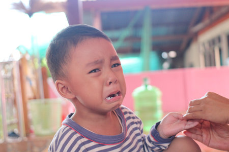 A sad young boy with tears streaming down his face expresses deep emotions. This intimate moment captures the innocence of childhood and the intensity of feelings.の写真素材