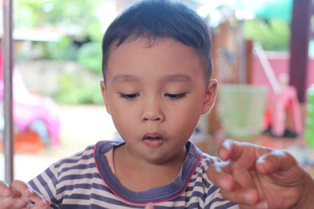 A young boy engaged in an activity outdoors, showcasing concentration and joy. This image captures the essence of childhood innocence and discovery.の写真素材