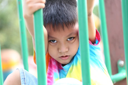 A curious child explores playground equipment with a playful expression. The vibrant colors highlight the joy and energy of childhood, making it perfect for capturing youthful adventures.の写真素材