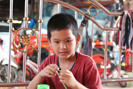 A young boy is engaged in a creative play activity at home, focusing intently on a green toy. His expression shows curiosity and joy, capturing a moment of innocence.の写真素材
