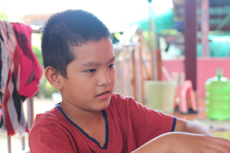 A young boy focused on an activity in a casual indoor setting, showcasing innocence and joy in a warm and inviting atmosphere. Great for childhood themes.の写真素材
