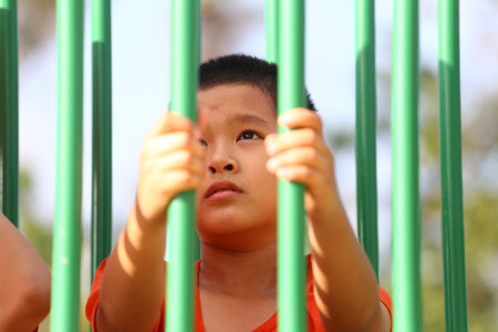 A young boy interacts with playground equipment, displaying curiosity and joy. The image captures a moment of childhood adventure in bright sunlight.の写真素材