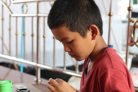 A young boy engaged in a craft activity, showcasing concentration and creativity. This portrait captures the essence of learning and personal expression in a simple indoor environment.の写真素材
