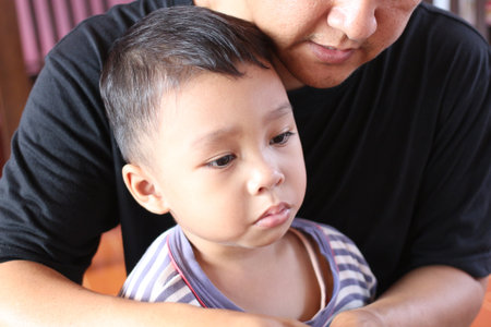 A heartwarming moment between a father and his child, showcasing love and tenderness in a serene indoor setting filled with natural light.の写真素材