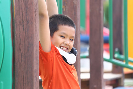 A cheerful boy enjoys playing at a colorful playground. His bright smile and playful pose capture...