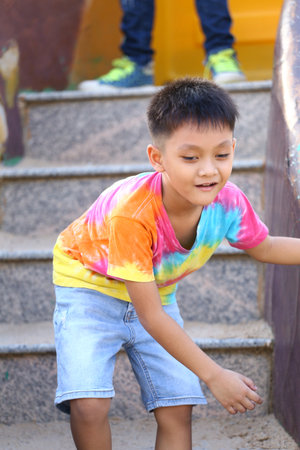 A joyful child playing on colorful stairs, showcasing vibrant clothing and a carefree spirit. This candid moment captures the essence of youth and fun outdoors.の写真素材