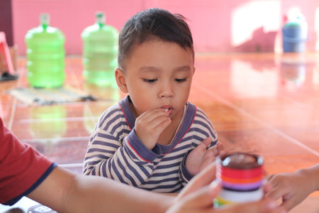 A young child engages with colorful objects, showcasing focus and concentration in a bright indoor setting. This scene captures the essence of childhood joy and exploration.の写真素材