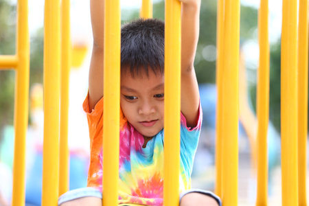 A young child enjoys playtime on a vibrant playground, showcasing joy and curiosity in a colorful tie-dye shirt, embodying the essence of childhood exploration.の写真素材