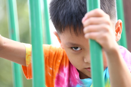 A focused child gripping playground equipment, showcasing determination. The bright colors emphasize the joy of childhood adventures in an outdoor setting.の写真素材