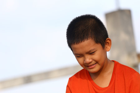 A young boy smiling under natural sunlight, embodying joy and innocence. His playful spirit shines through in this heartwarming outdoor portrait.の写真素材