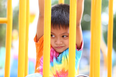A joyful child plays on colorful playground equipment, showcasing innocence and energy. This cheerful moment captures the essence of childhood leisure and fun.の写真素材