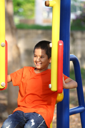 A joyful child enjoying playtime on a colorful playground. The boy's cheerful smile and sunlight bring a sense of happiness and carefree fun in an outdoor setting.の写真素材