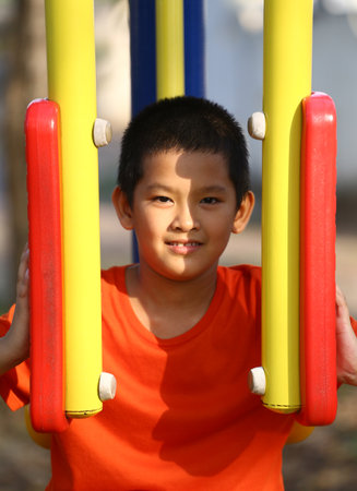 A cheerful boy enjoys playing in the sunlight on colorful playground equipment, capturing the essence of childhood joy and vibrant outdoor activities.の写真素材