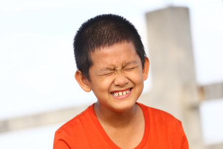 A joyful child laughs heartily, showcasing pure happiness in an outdoor setting. The bright, natural light highlights the carefree spirit and youthful energy.の写真素材