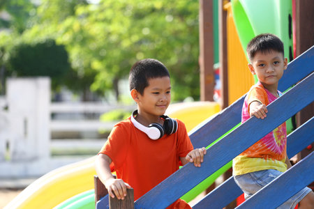 Two joyful children enjoy their time at a vibrant playground, climbing the colorful stairs. The scene captures the essence of childhood adventure and friendship.の写真素材
