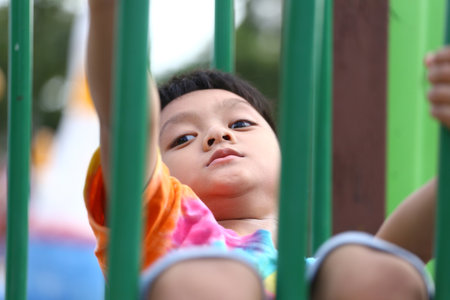 A young child enjoys climbing on playground equipment, demonstrating joy and exploration. The vibrant colors emphasize a playful outdoor atmosphere.の写真素材