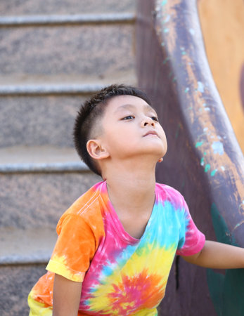 A curious child stands on playground steps, wearing a bright, colorful shirt. The scene captures the essence of childhood exploration and joy.の写真素材
