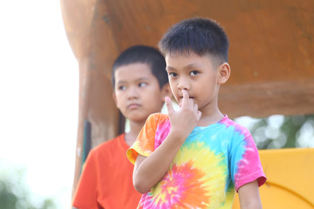 Two young boys enjoy an outdoor moment, showcasing their playful spirits. One wears a colorful tie-dye shirt, expressing innocence and joy in nature.の写真素材