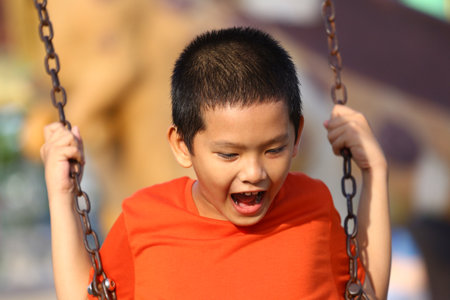 A joyful child experiences the thrill of swinging in a vibrant playground. This image captures the essence of childhood excitement and happiness.の写真素材