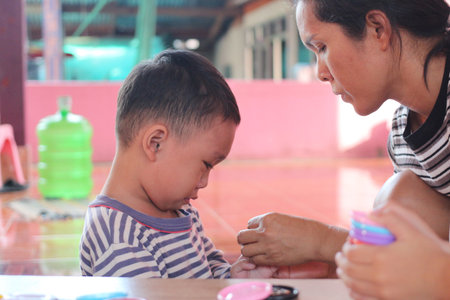 A tender moment showcasing a mother engaged with her son during a playful activity, emphasizing bonding, creativity, and nurturing in a vibrant indoor setting.の写真素材