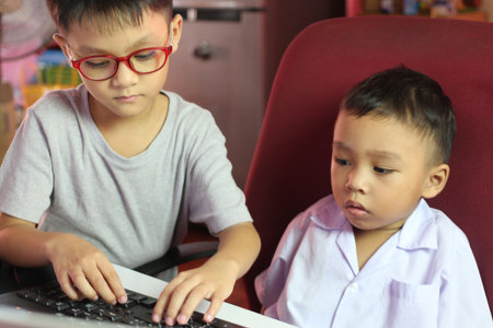 Two children engage in a learning moment at a computer, exploring technology together. The scene captures curiosity and teamwork in a fun, casual setting.の写真素材