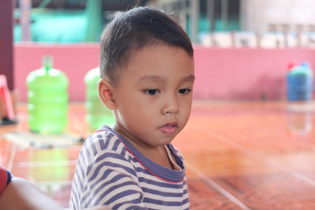 A close-up portrait of a thoughtful young child indoors, displaying an innocent expression. The colorful background creates a vibrant atmosphere, emphasizing childhood moments.の写真素材