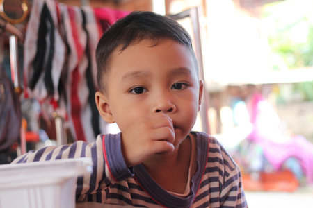 A close-up portrait of a young boy deep in thought, showcasing a casual and warm environment. The child's innocent expression radiates curiosity and joy.の写真素材