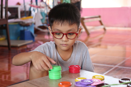 A young boy engages in play with colorful stacking toys, showcasing focus and creativity in a home...