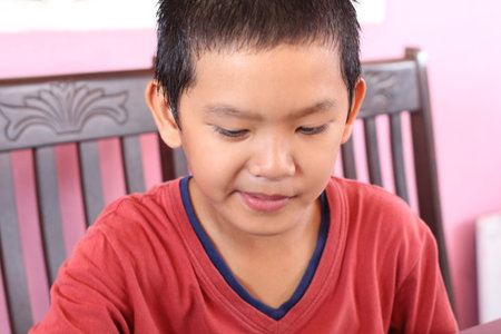 A young boy demonstrates concentration while engaging in a creative activity indoors. His focused expression captures the essence of childhood joy and curiosity.の写真素材