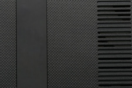 Close-up view of a textured black surface featuring a groove and ventilation slots, ideal for...