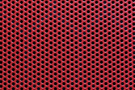 A bright red perforated metal sheet featuring uniform holes, perfect for various design, industrial, and creative applications, enhancing aesthetics and functionality.の写真素材
