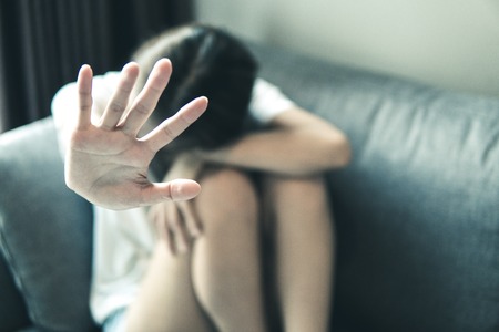 Women abused in her home holding her hand up. Stop sexual harassment against women. Violence and...