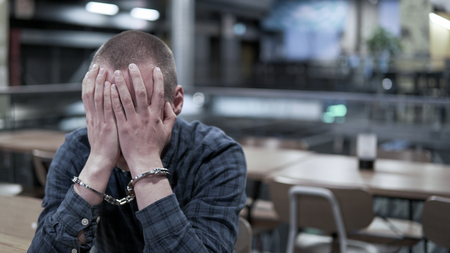 Criminal hold his hands in front of face after beeing subject to arrest. Regret.の写真素材